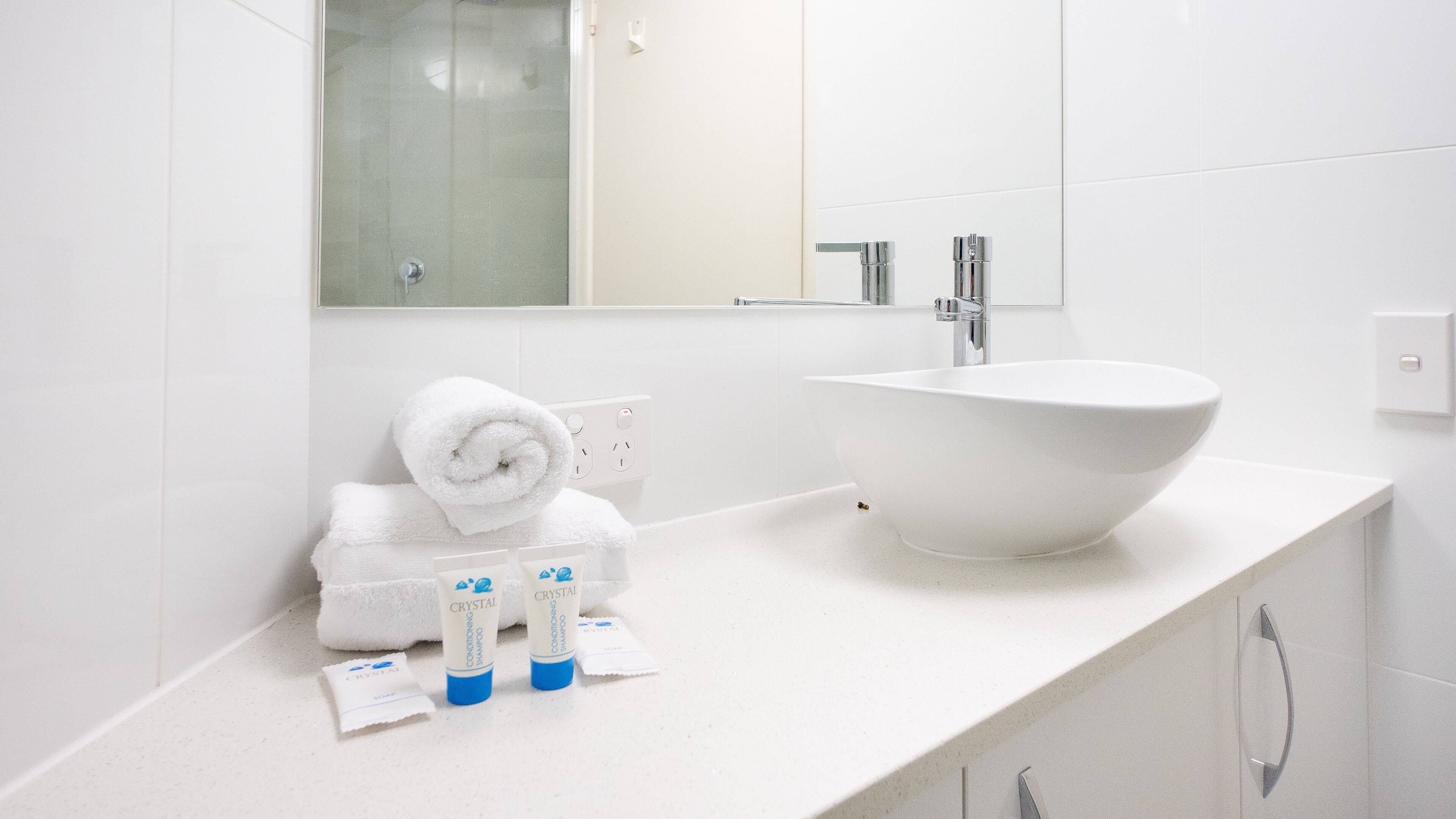 A modern bathroom with a large white sink, a mirror, and a towel rack.