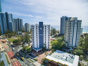 A high-rise hotel with a prominent 'Alexander' sign, surrounded by other tall buildings and a view of the ocean.