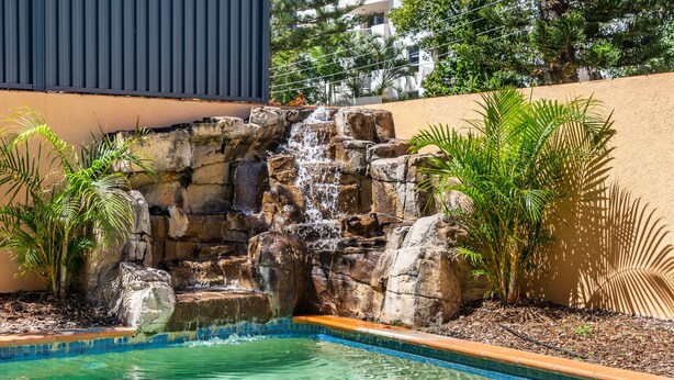 Una piscina con una cascada rodeada de rocas y plantas.