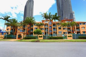 A hotel with a central courtyard, palm trees, and two tall cylindrical towers.