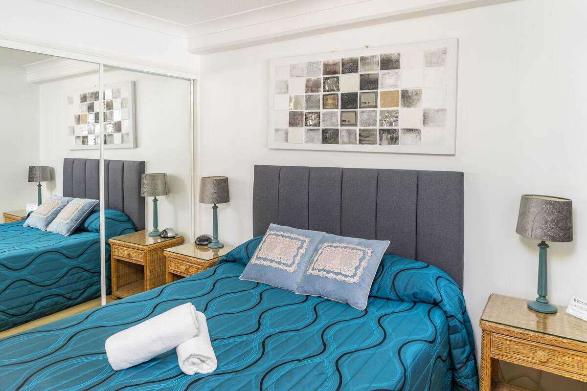 Habitación de hotel con dos camas, un espejo grande y obras de arte en las paredes.