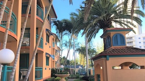 Un patio con una fuente, palmeras y un edificio con balcones.