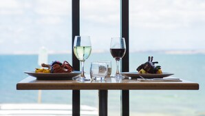 A table with plates of food and wine glasses, overlooking a body of water. - Ozone Hotel Kangaroo Island (Kingscote)