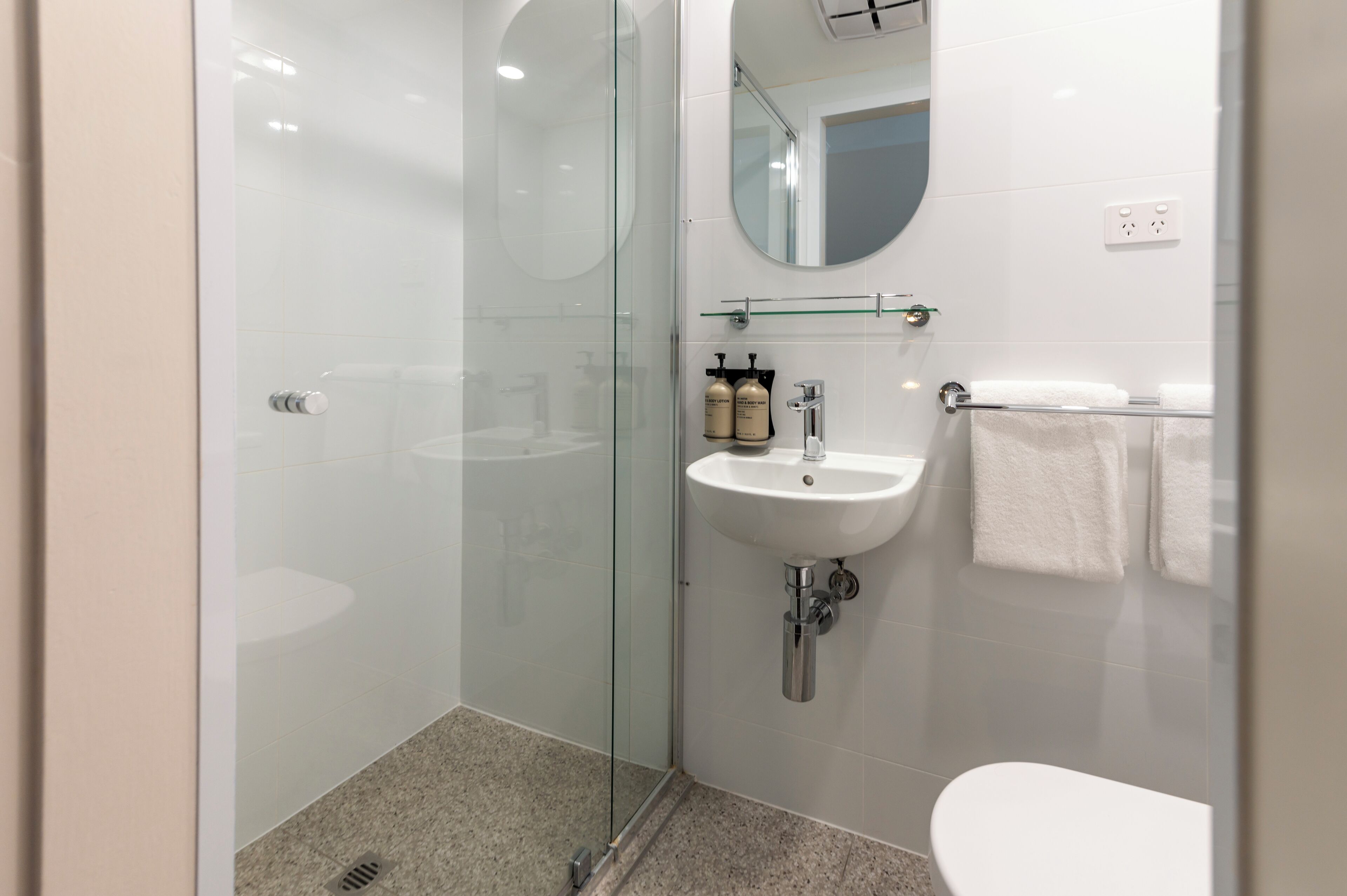 A modern bathroom with a glass-enclosed shower, a white sink, and a toilet.