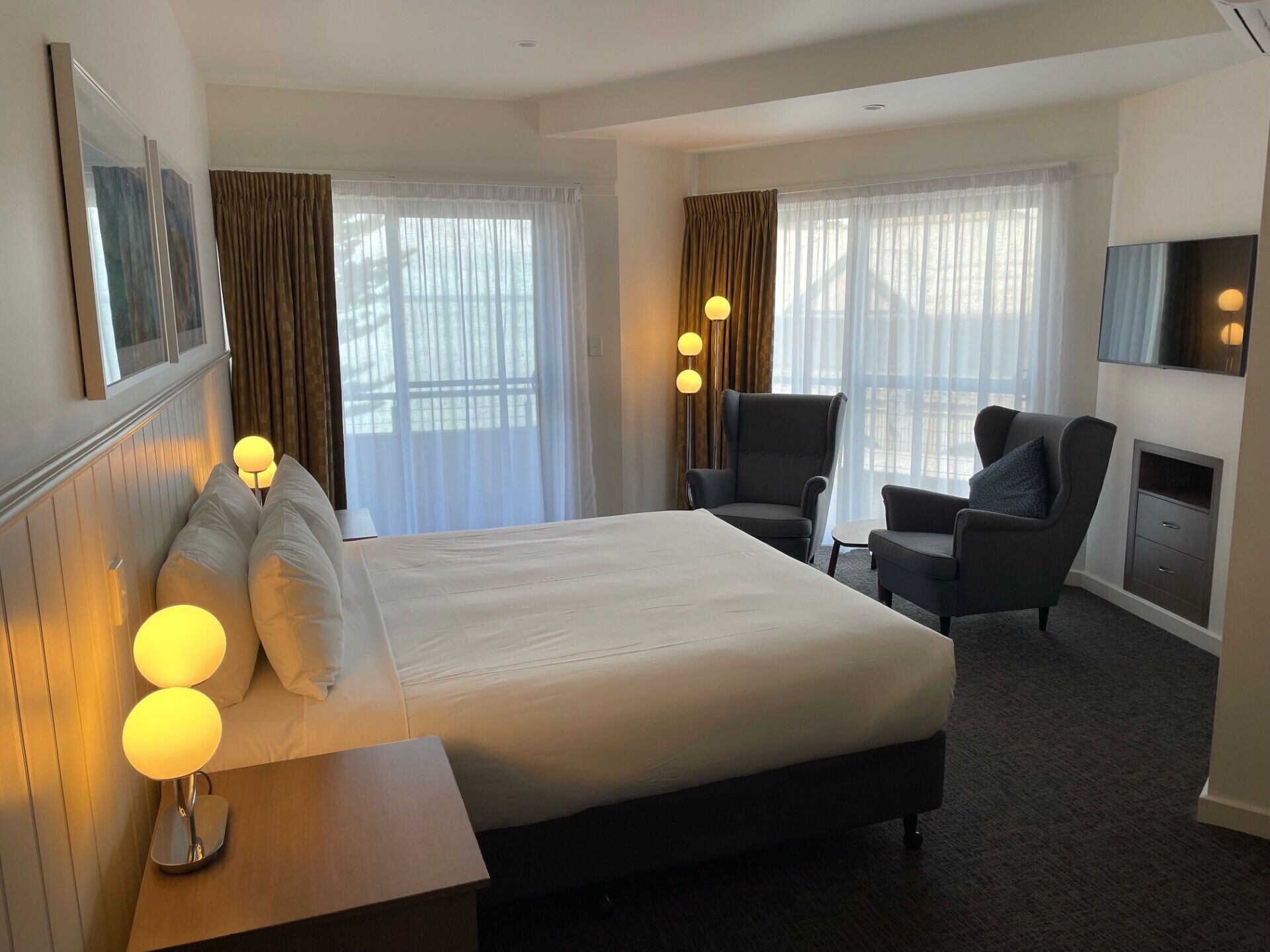 Een hotelkamer met een groot bed, twee fauteuils, een flatscreen televisie en een open haard.