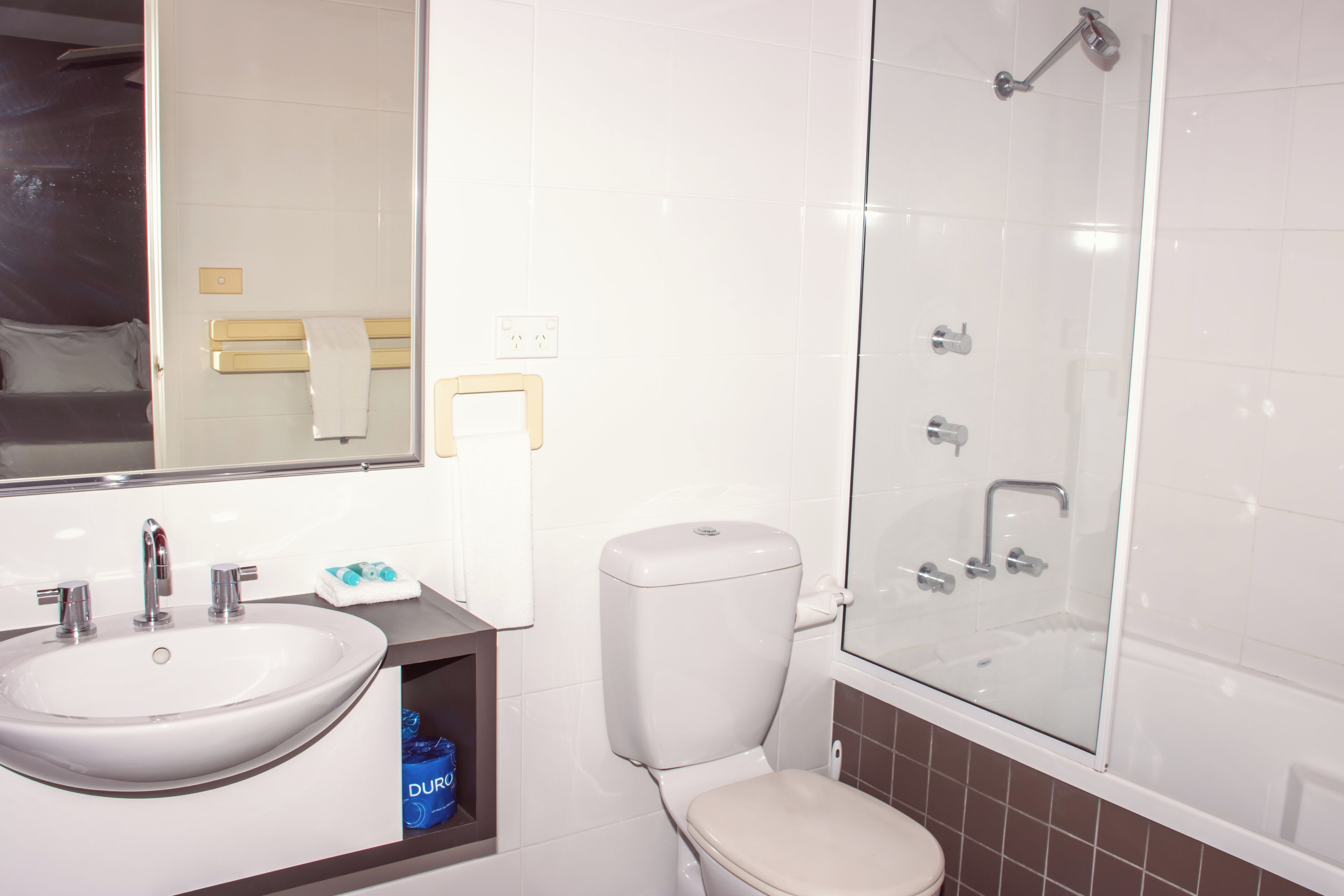 Une salle de bain équipée d’un lavabo, de toilettes et d’une douche à parois de verre.