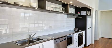 Une cuisine moderne avec des armoires blanches, des appareils en acier inoxydable et un plancher en bois.