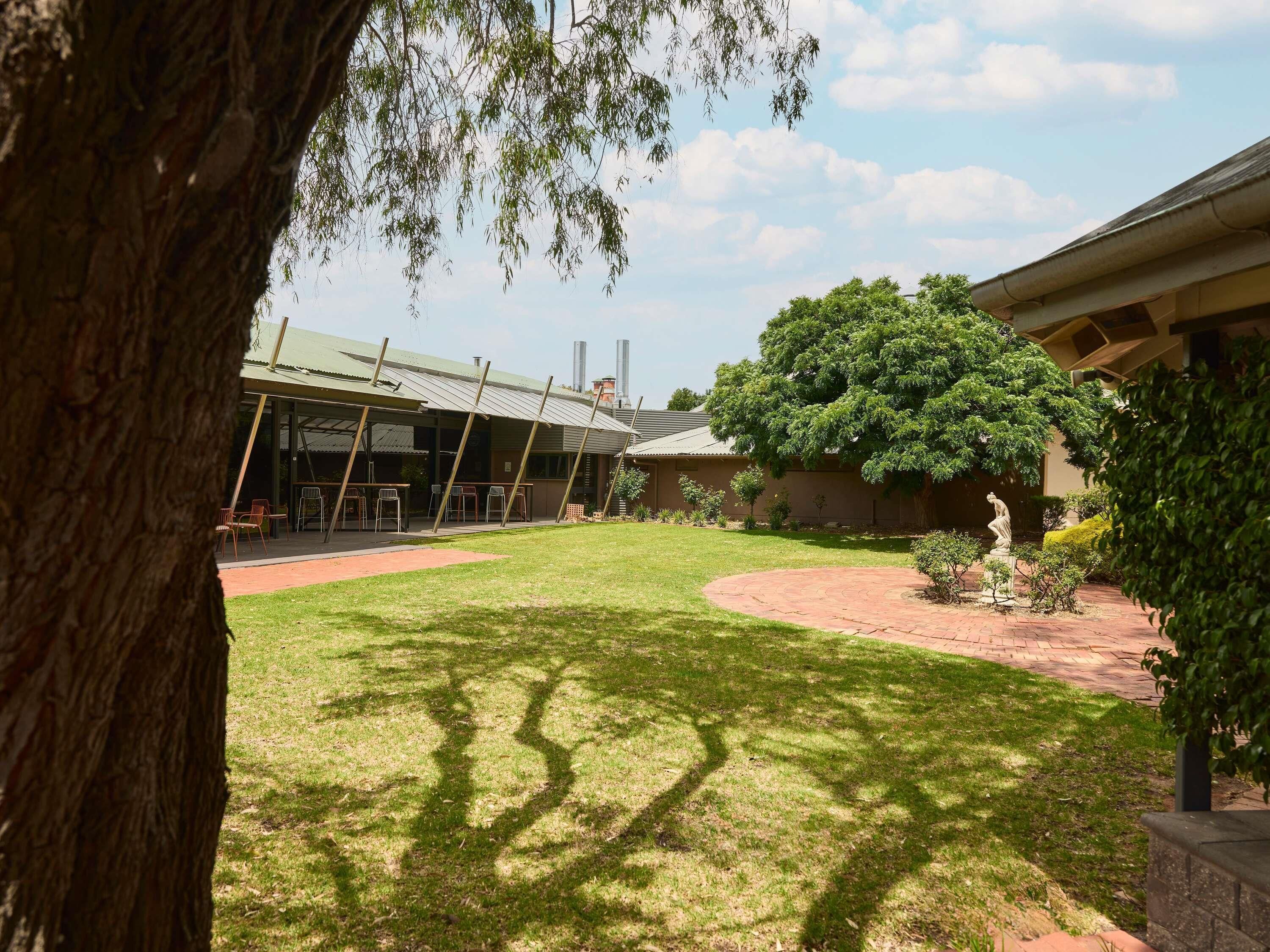 Un patio con césped, una zona de estar techada y una estatua.