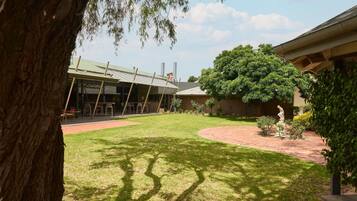 Un patio con césped, una zona de estar techada y una estatua.