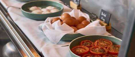 Un bufé con diversos alimentos, como huevos, pan y tomates.