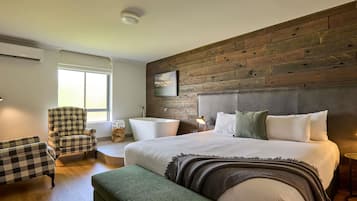A modern bedroom with a large bed, a wooden accent wall, a checkered armchair, and a small side table.
