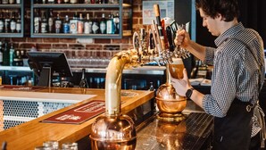 A bartender at a bar with a beer tap and a cash register. - Mercure Barossa Valley (Tanunda)