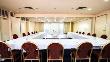 A conference room with a long table and chairs, large windows, and a view of the city.