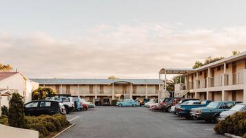 A parking lot with several cars parked in front of a motel with multiple balconies.