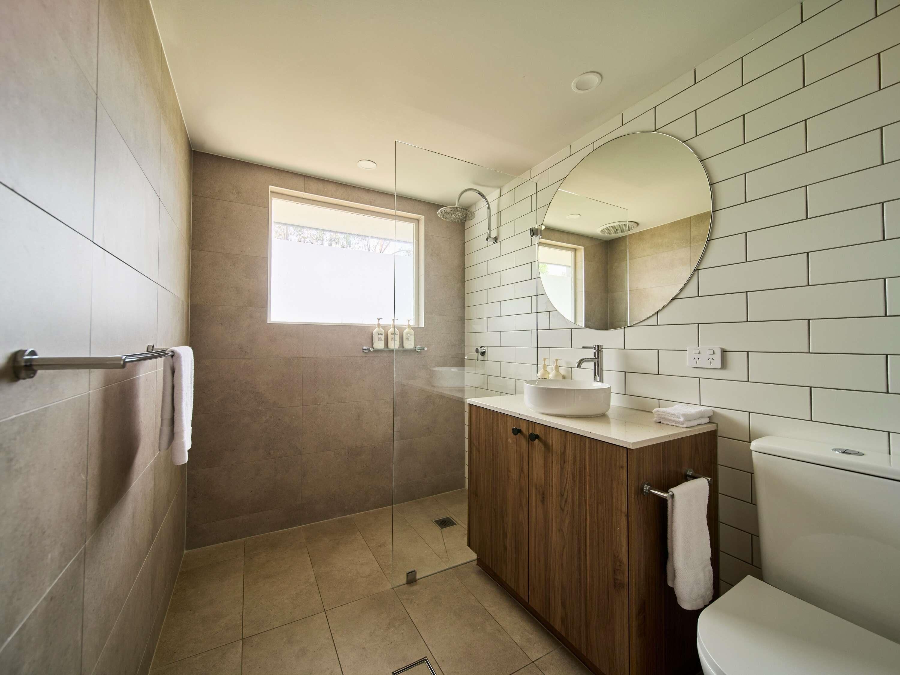 A modern bathroom with a walk-in shower, a vanity with a sink, and a toilet.