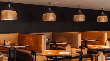 A restaurant interior with booth seating, tables, and hanging pendant lights.