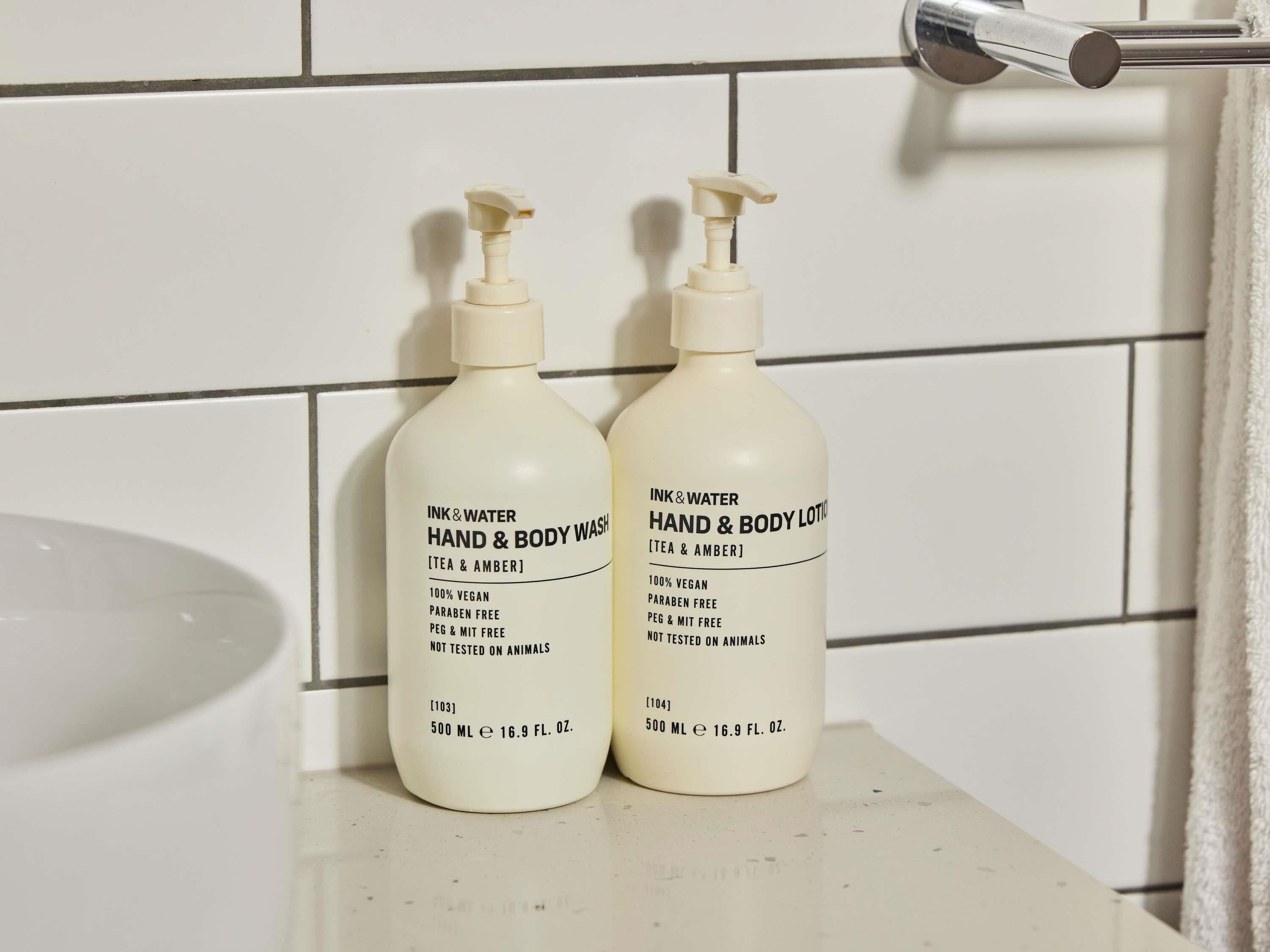 Two bottles of hand and body wash on a bathroom counter.