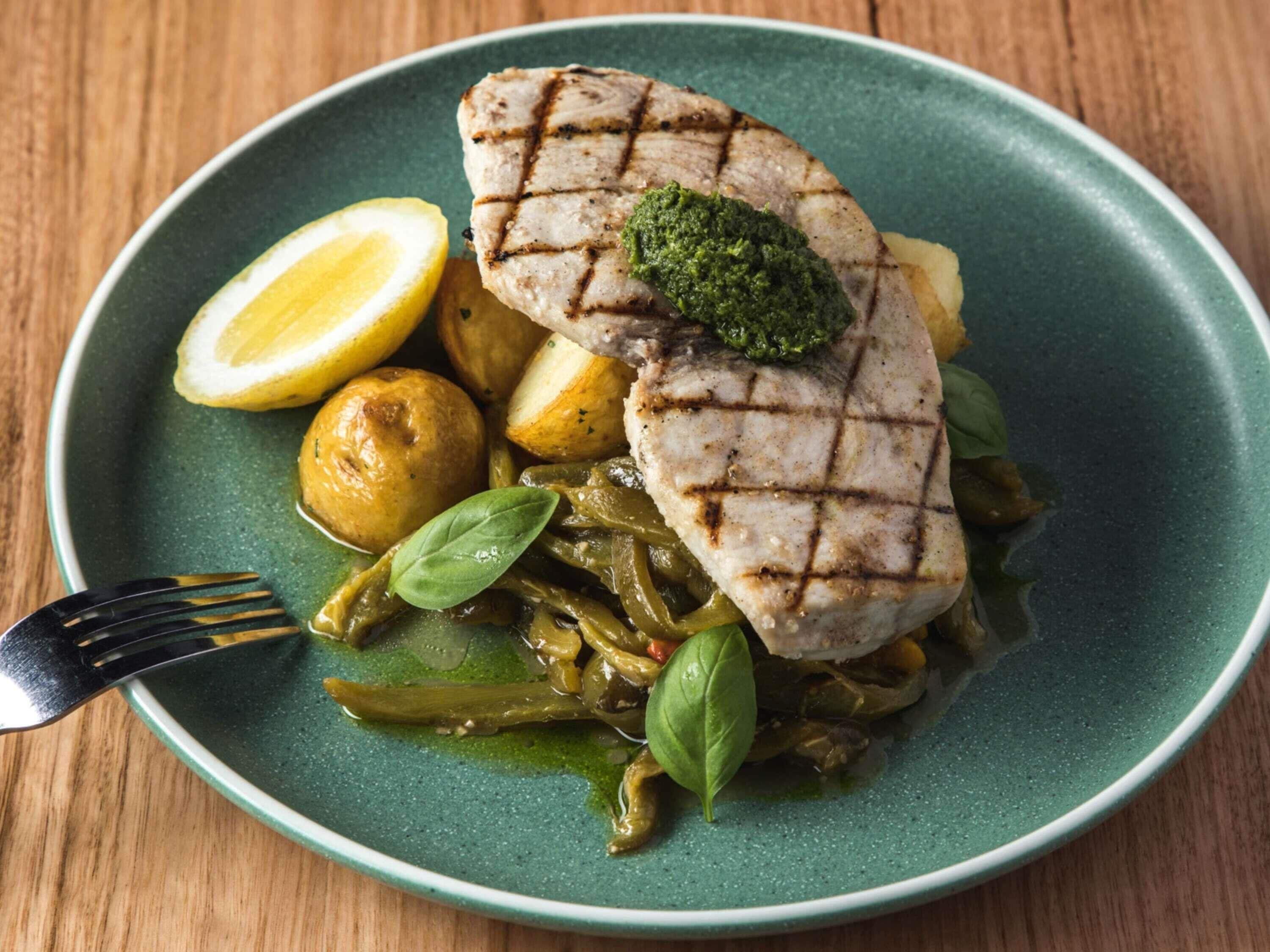 Ein Teller mit gegrilltem Fleisch, Kartoffeln und grünen Gemüsesorten, vermutlich eine Mahlzeit.
