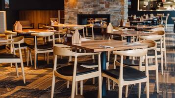 Un interior de restaurante con mesas y sillas de madera, una pared de piedra y una chimenea.