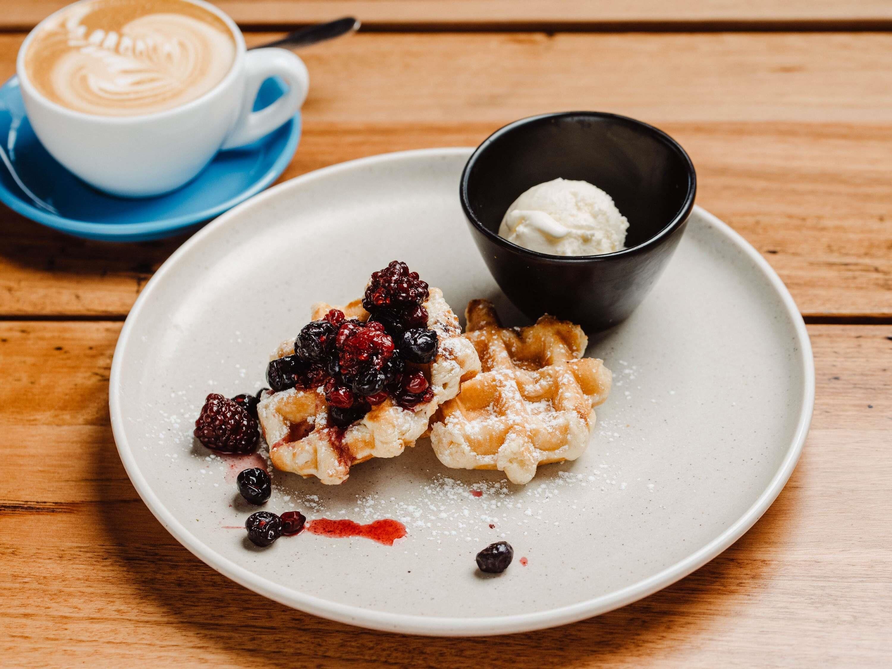 A plate with a dessert, a cup of coffee, and a small bowl of ice cream.