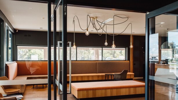 A modern interior with a wooden bench, seating area, and a glass partition. - Mercure Barossa Valley (Tanunda)