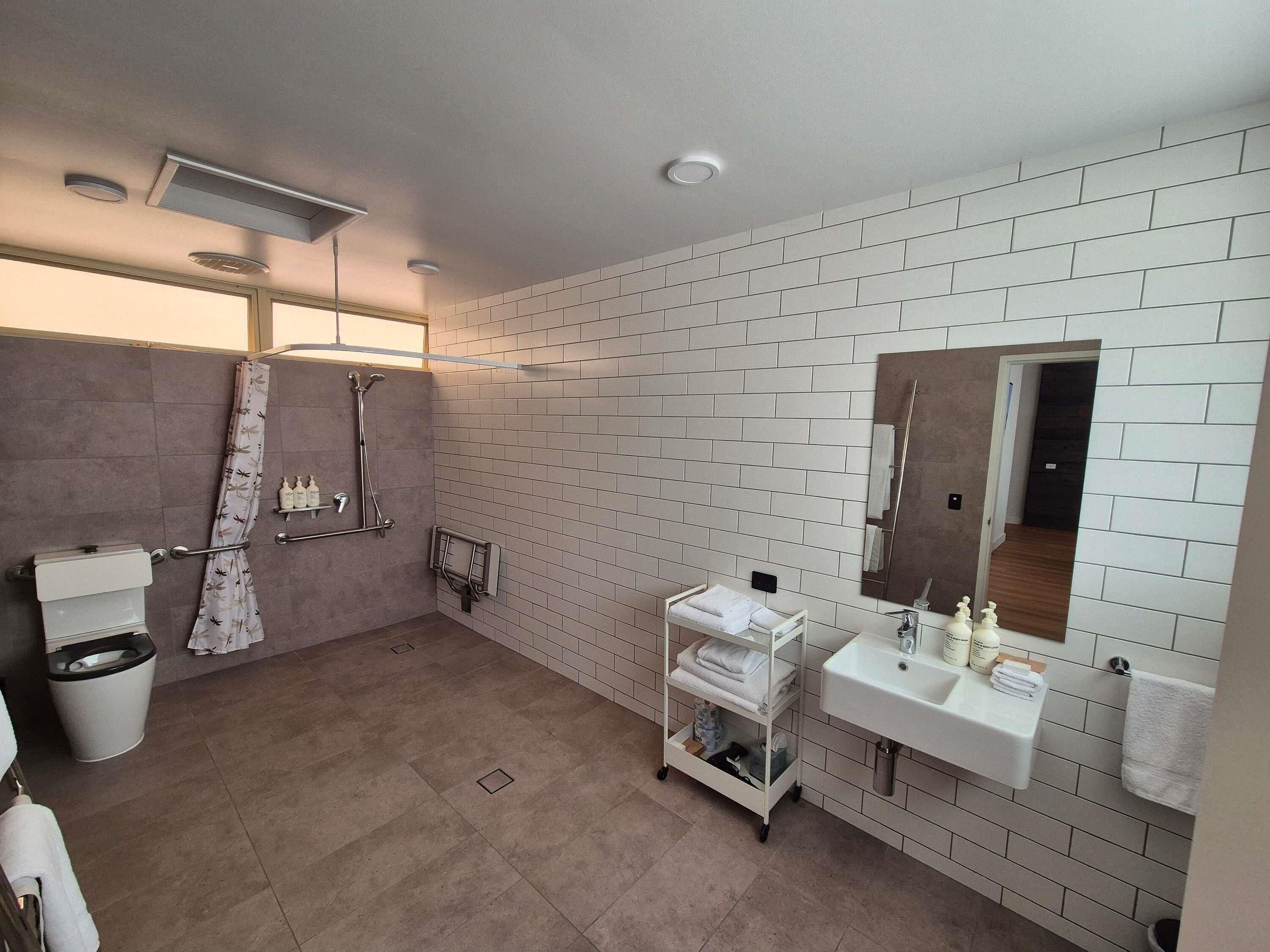 A modern bathroom with a shower, toilet, sink, and a mirror.