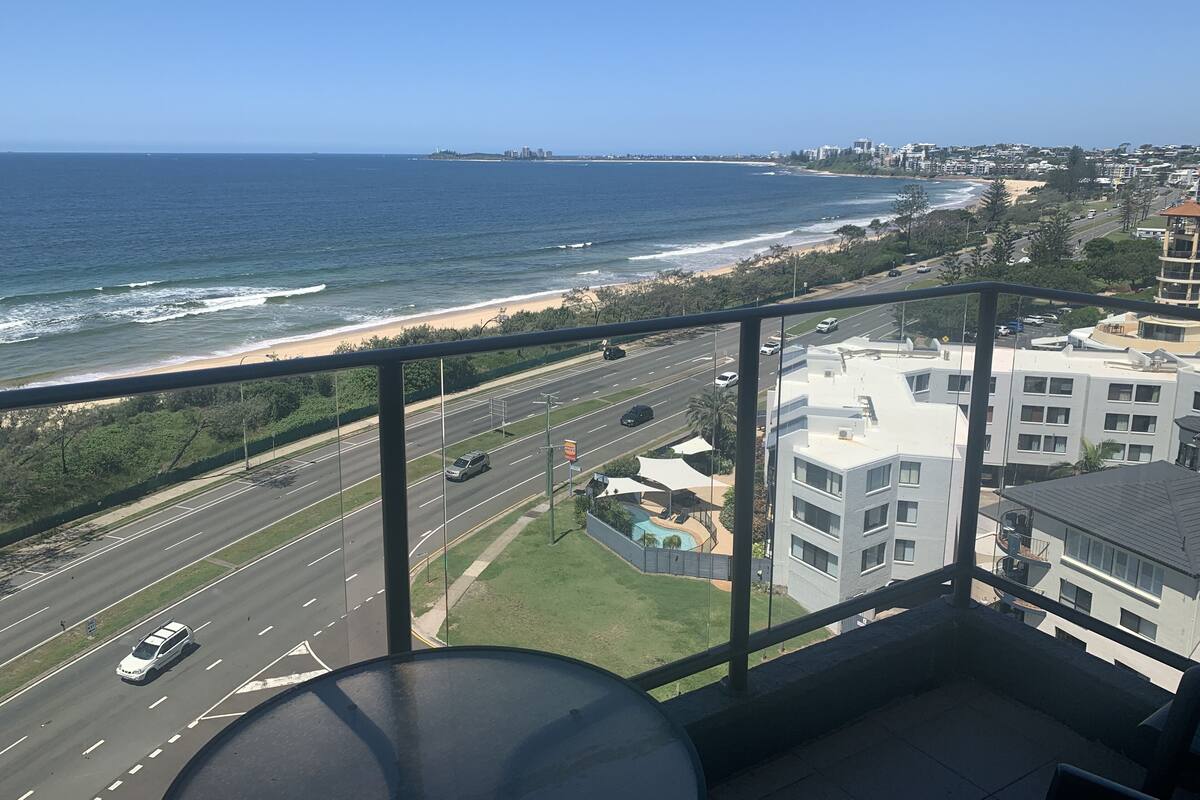 A balcony with a view of the ocean and a busy road.