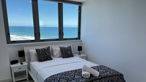 Una camera da letto con un letto, due comodini, una finestra vista mare e un pavimento in marmo.