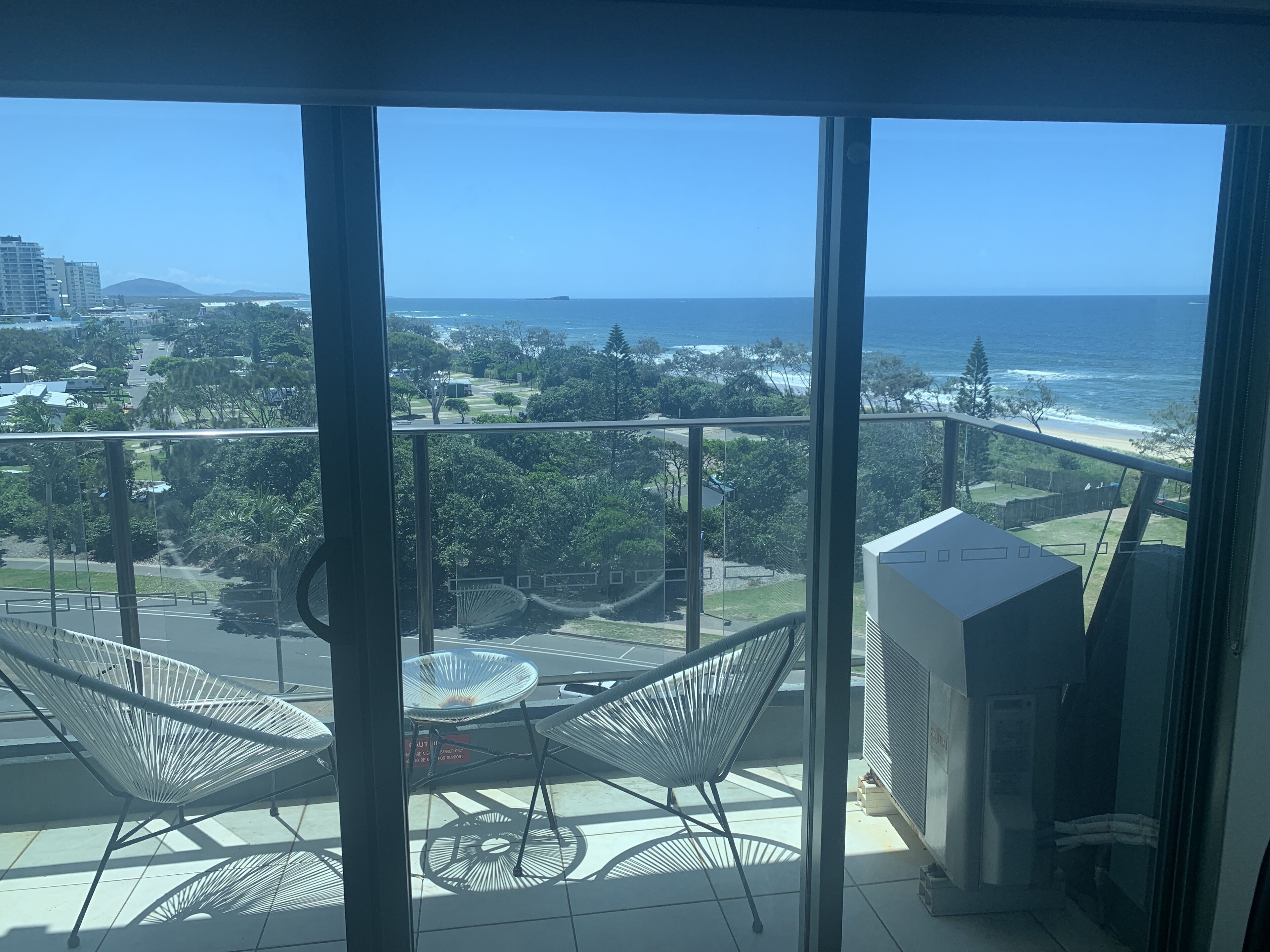 A balcony with a view of the ocean and cityscape.