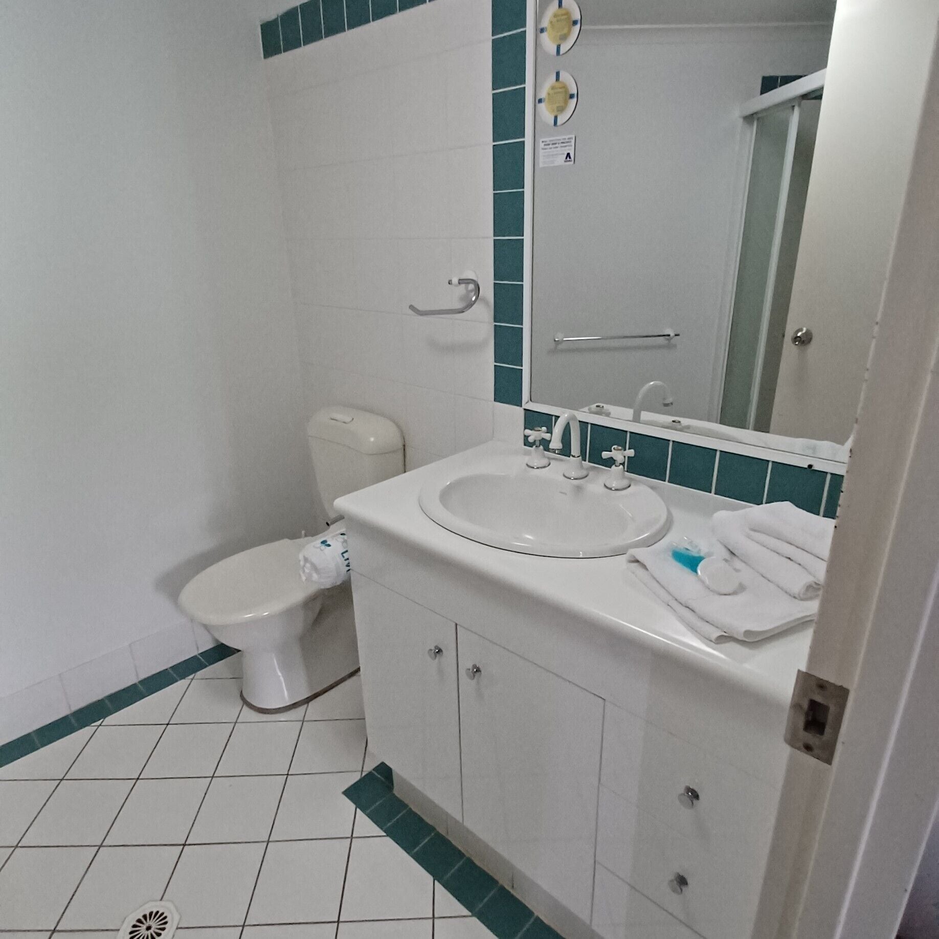 A bathroom with a toilet, sink, and mirror.