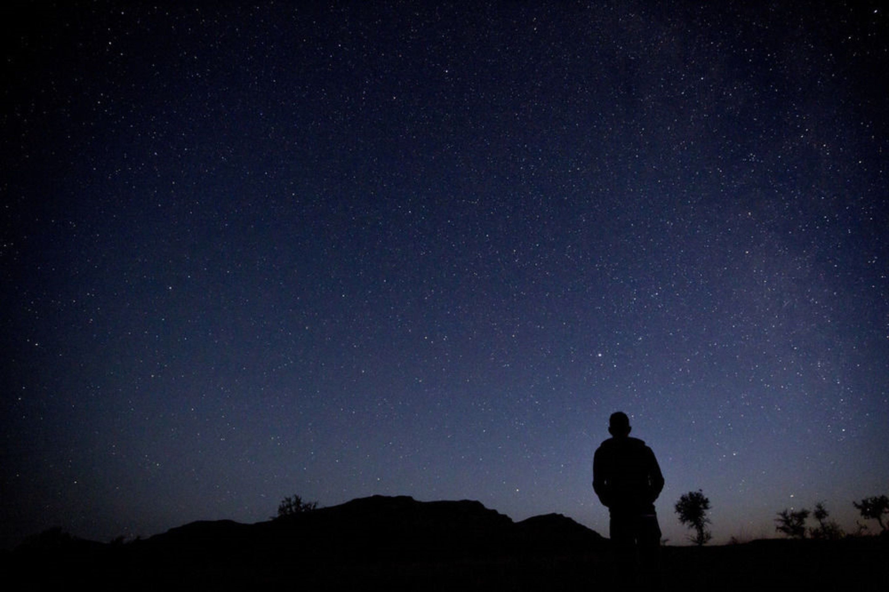 A person standing under a starry night sky.