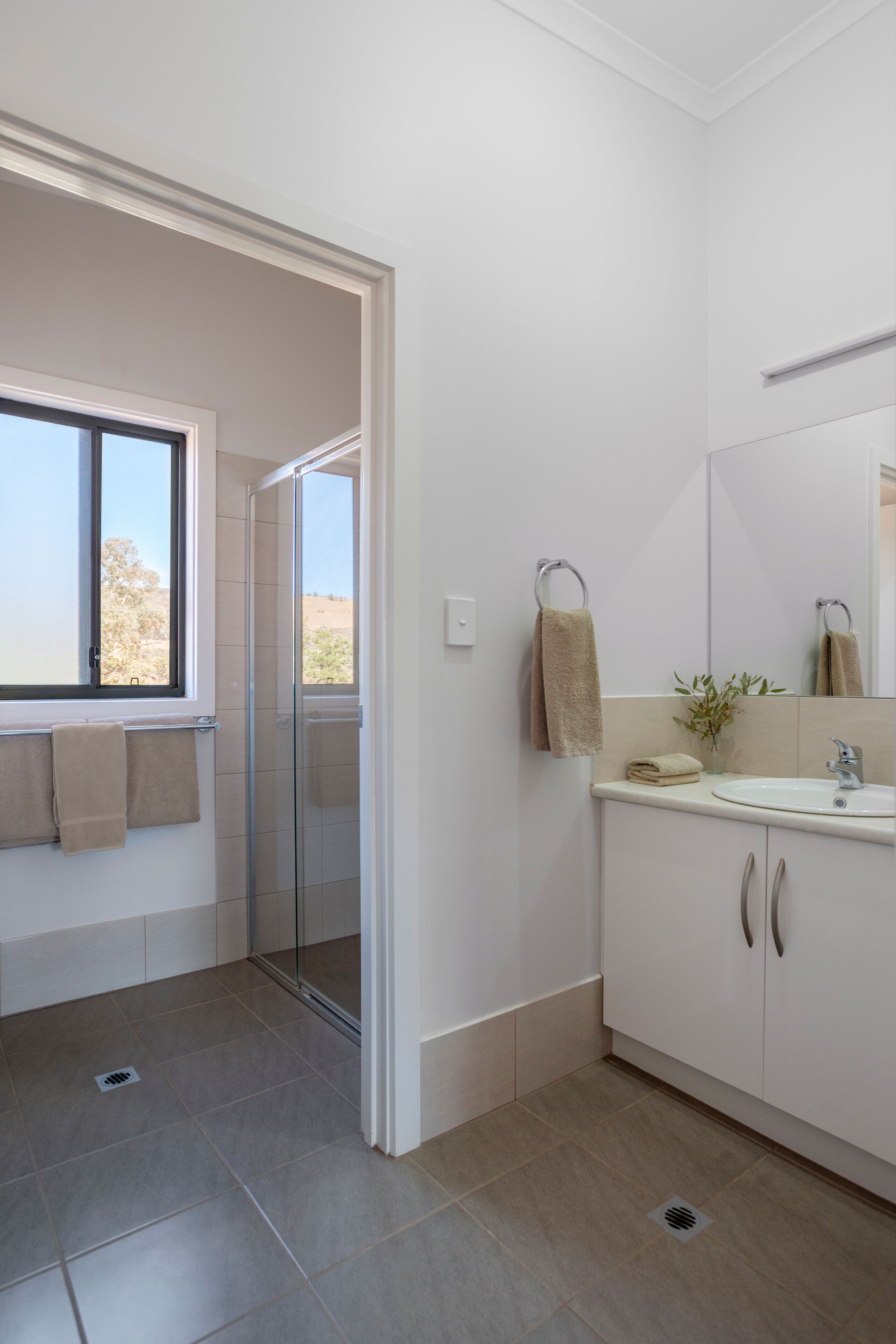 Un baño moderno con ducha de vidrio, un lavabo con espejo y una ventana con vistas al exterior.