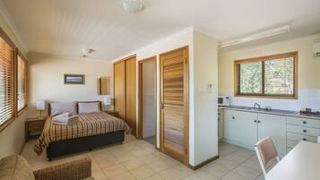 A bedroom with a bed, bedside table, and a window with blinds.