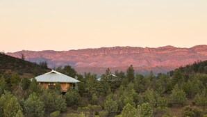 Una casa con techo blanco rodeada de árboles y montañas al fondo.