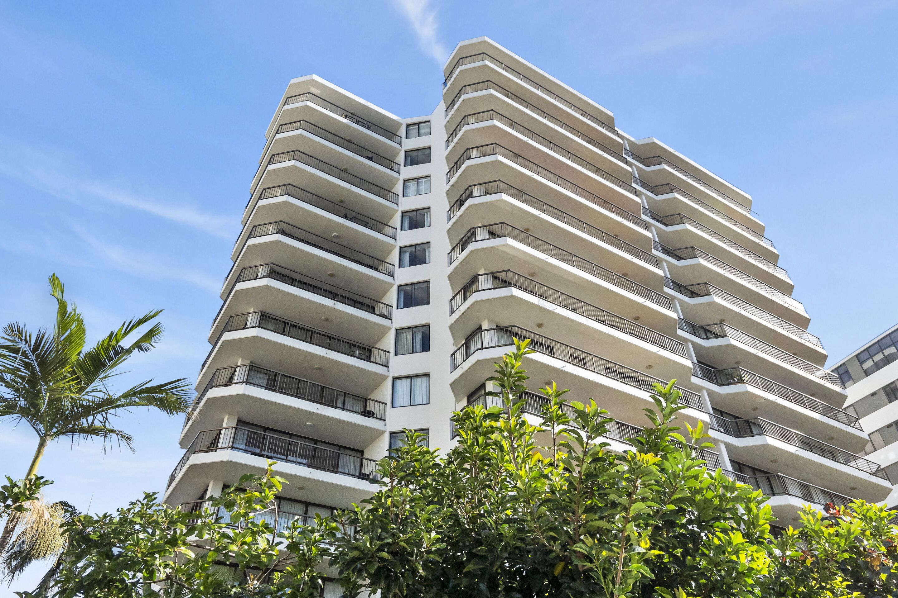 A modern high-rise building with multiple balconies and a clear sky.