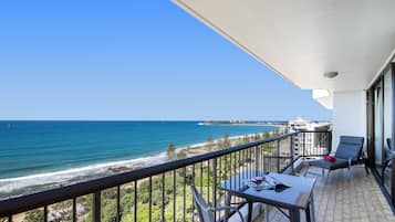 Enjoy the ocean view from this balcony with a table and two chairs.