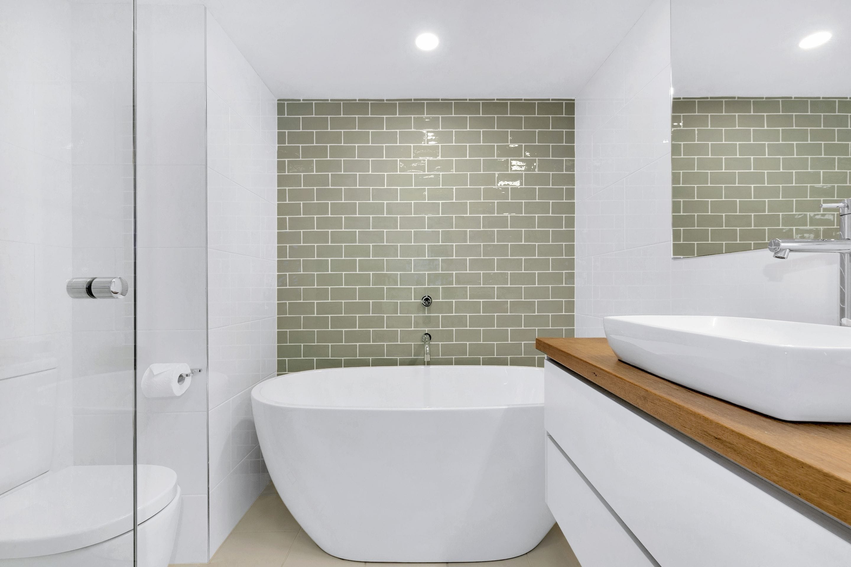 A modern bathroom with a freestanding bathtub, a glass shower enclosure, and a wooden vanity with a white sink.