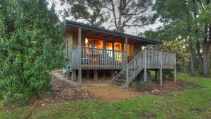 A cabin with a wooden deck, a staircase, and a covered porch area. - Stewarts Bay Lodge (Port Arthur)