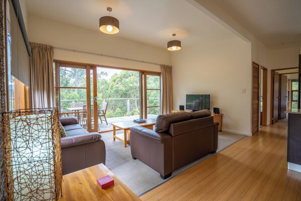 A spacious living area with a sofa, a TV, and a dining table. - Stewarts Bay Lodge (Port Arthur)