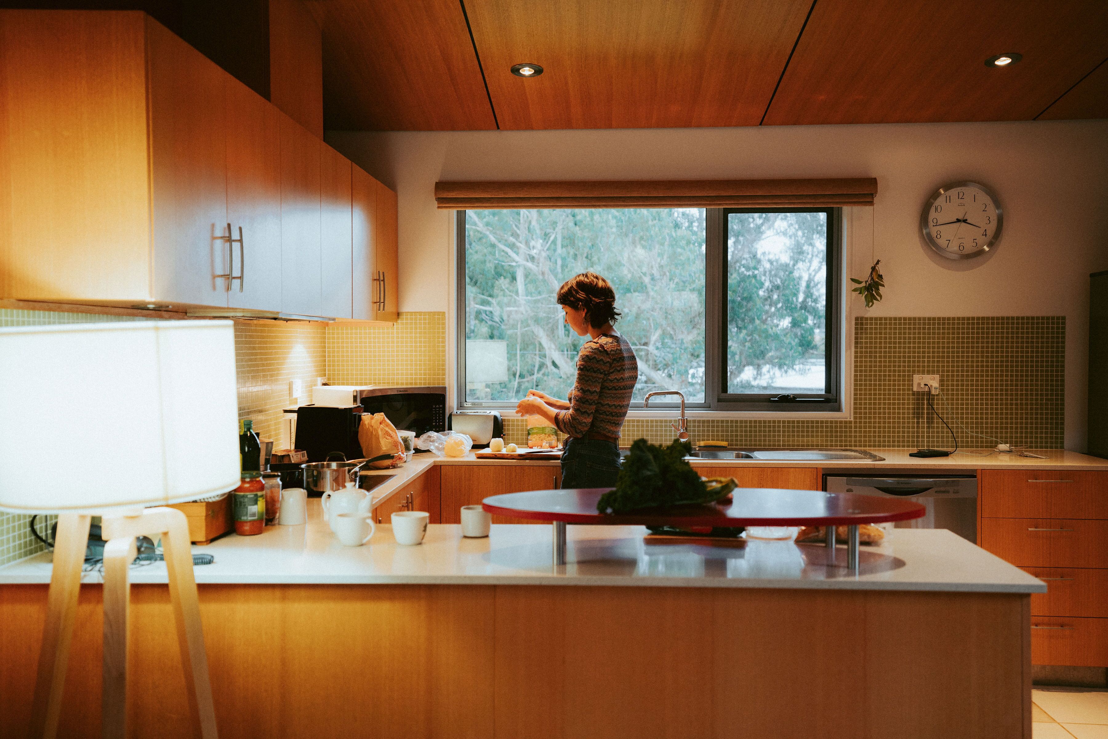 Una cocina moderna con armarios de madera, un ventanal grande y un reloj en la pared.