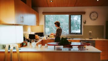 A modern kitchen with wooden cabinets, a large window, and a clock on the wall.