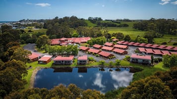 Situated in a lush landscape, this hotel complex features multiple buildings arranged around a serene central courtyard with a small pond.