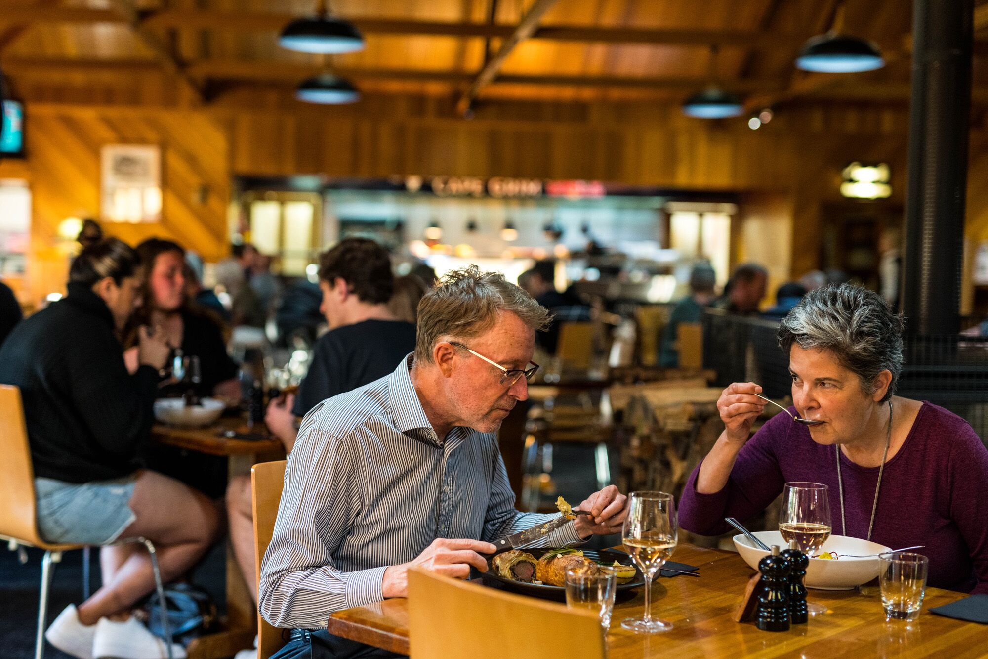 A restaurant with wooden interiors and patrons dining.