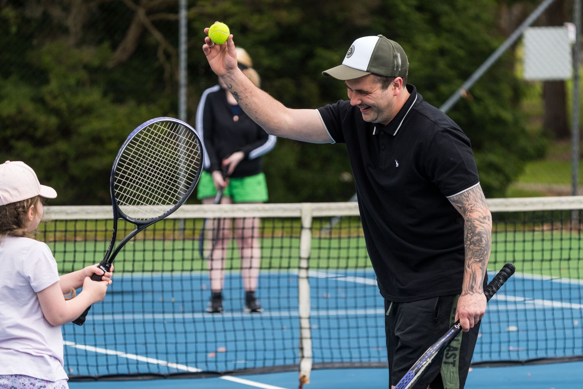 A tennis court with a net, a tennis ball, and a racket.