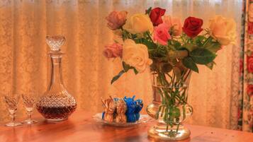 A table with a vase of roses, a crystal decanter, and glass cups.