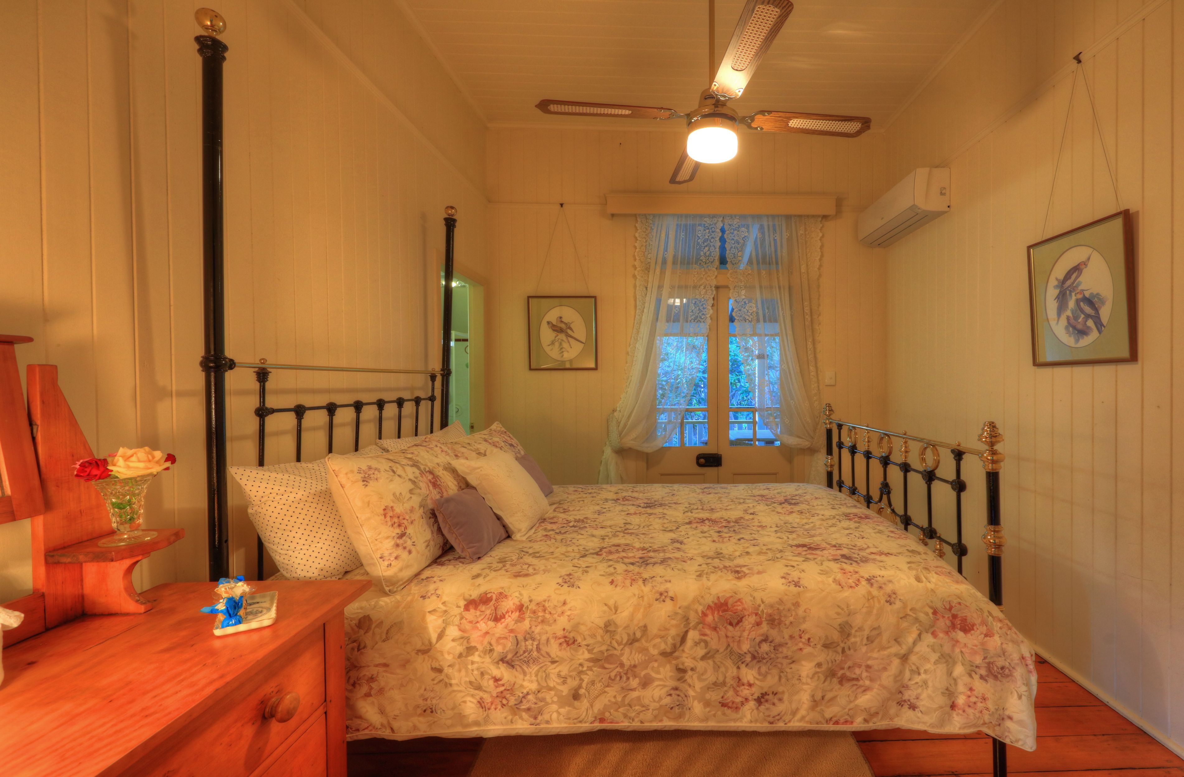 Un dormitorio con cama, mesita de noche de madera y ventilador de techo.