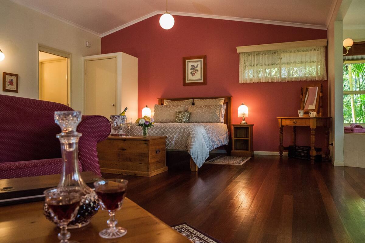 Een gezellige slaapkamer met een bed, een houten dressoir en een nachtkastje met een lamp.