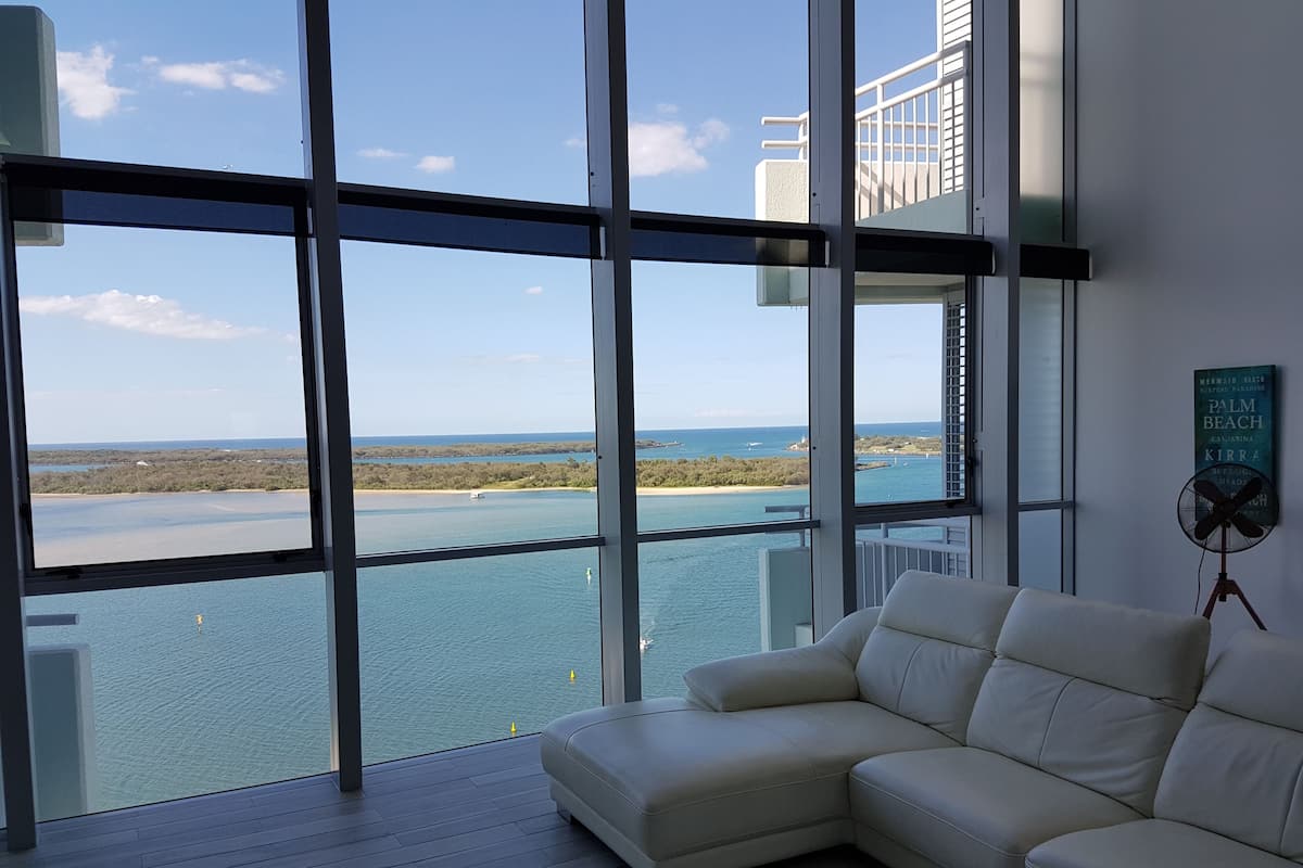 Ein modernes Wohnzimmer mit einem großen Fenster und Blick auf die Küste.