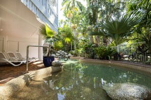 A pool area with lounge chairs, a palm tree, and a stone pathway. - The White House Port Douglas (Port Douglas)
