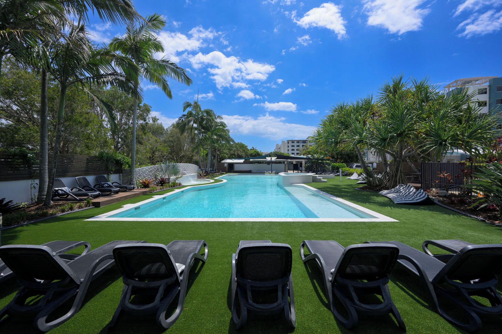 Una piscina al aire libre, sillones reclinables de piscina